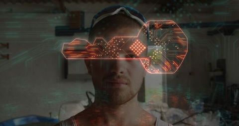 Man standing in garage wearing goggles displaying holographic circuit key and neon glow