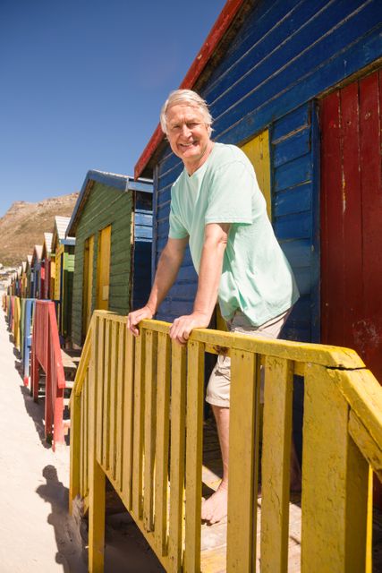 Portrait of smiling senior man standing at beach house on sunny day