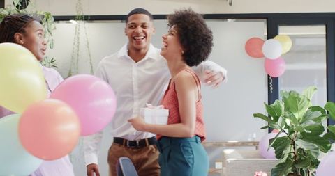 Co-workers Celebrating with Balloons and Gift in Modern Office