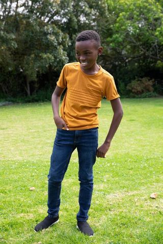 Young boy smiling in garden wearing stylish casual outfit