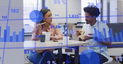 Colleagues Sharing Lunch While Discussing Data Overlaid with Blue Charts and Graphs
