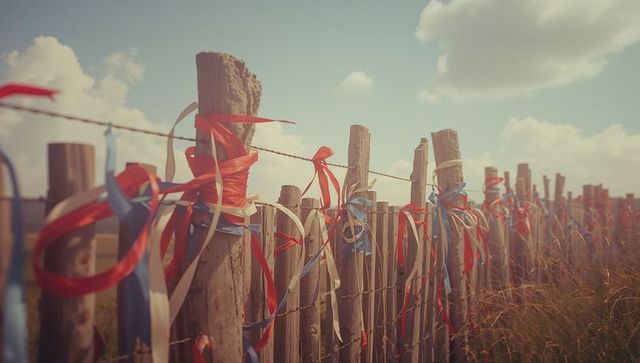 Festive ribbons on rustic rural fence in sunlit countryside