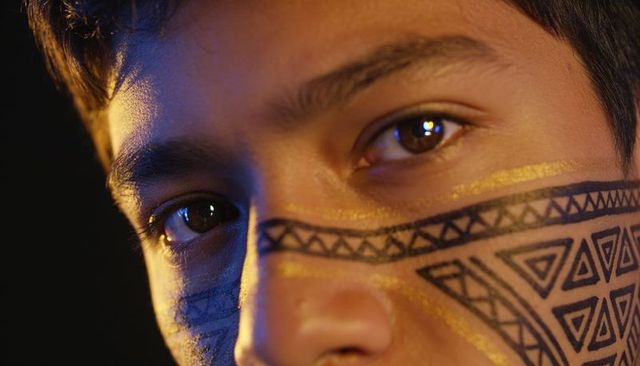 Closeup male teen face with geometric black and gold metallic paint under dramatic lighting