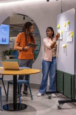 Diverse coworkers collaborating in modern office nook during sticky-note brainstorming session
