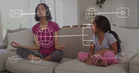 Mother meditating while guiding daughter on sofa with digital connectivity icons overlay