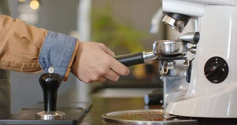 Barista holding portafilter under espresso machine group head preparing espresso shot