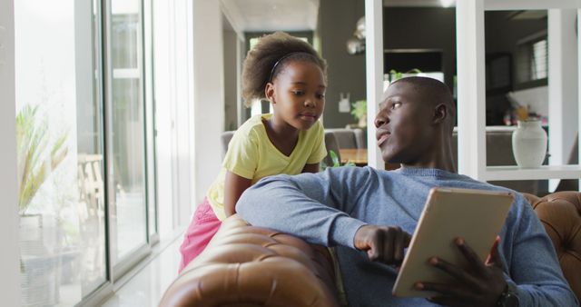 Image of african american father and daughter using tablet. Enjoying quality family time together at home, using technology.