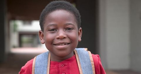 Smiling African American Schoolboy in Corridor with Denim Backpack