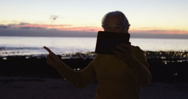 Elderly Person Enjoying Sunset on Beach with Tablet - Download Free Stock Images Pikwizard.com