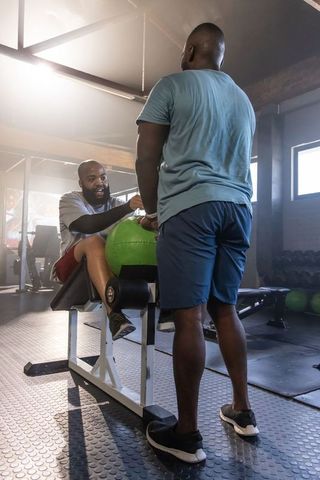 African american men partner training with green medicine ball on decline bench in gym