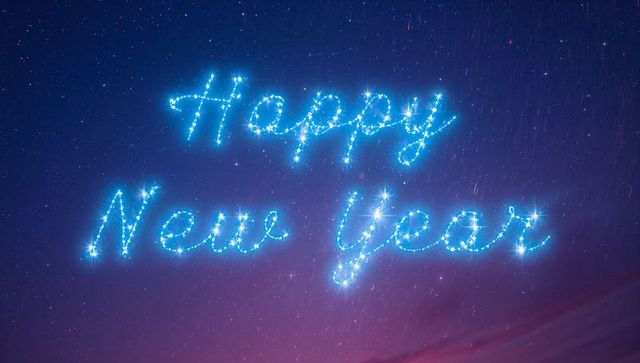 Glowing cursive happy new year lettering in sparkling star lights across cosmic night sky