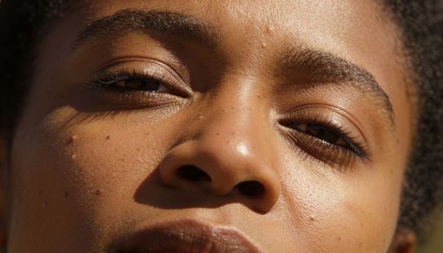Sunlit closeup portrait of female face showing natural skin texture, pores and eyelashes