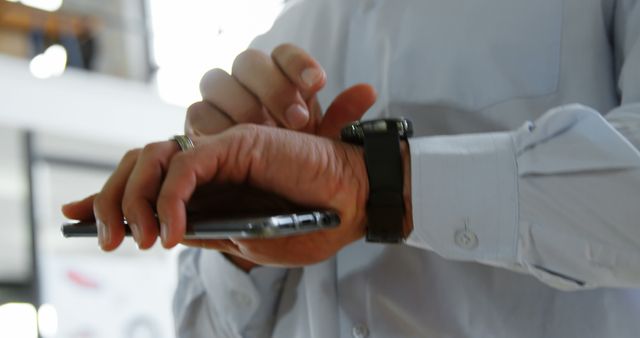 Businessman Using Smartwatch and Smartphone in Office - Download Free Stock Images Pikwizard.com