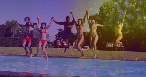 Group of friends laughing and jumping into backyard pool