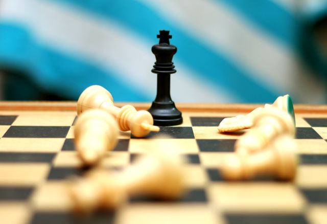 This close-up view depicts a chess game in progress with several fallen pieces and a prominent standing black king figurine. The image signifies themes of strategy, competition, and victory which could be used in educational materials, presentations on strategic thinking, articles about the game of chess, or promotional content for chess events.