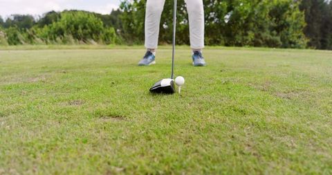 Senior woman preparing to tee off on scenic golf course