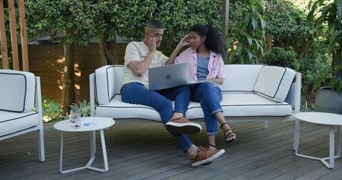 Diverse Couple Collaborative Work on Garden Patio with Laptop