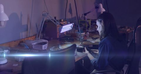 Focused Artisan Crafting Jewelry in Dimly Lit Workshop