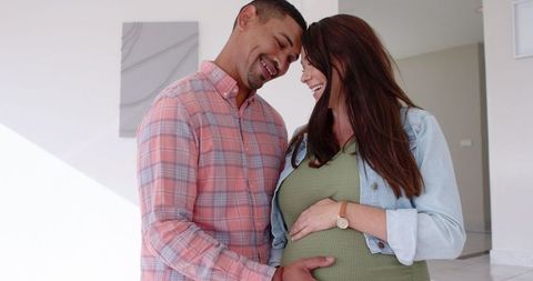 Joyful couple cradling pregnancy for loving moment in modern home