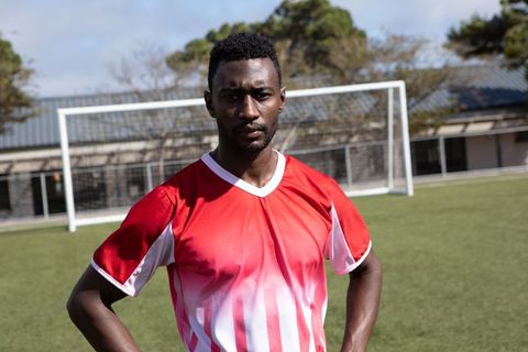Confident soccer player posing near soccer goal on bright day