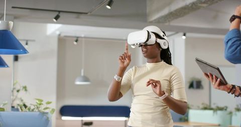 Woman wearing VR headset interacting with virtual interface in modern coworking office