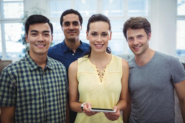 Group of smiling business executives standing together in a bright office environment. The individuals are wearing casual attire and appear positive and professional. Suitable for use in business and teamwork-related content, professional development materials, and corporate communications.