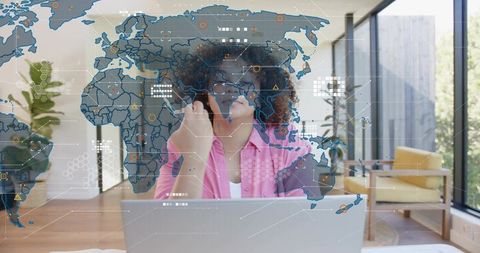 Remote worker holding phone and viewing laptop with holographic world map overlay