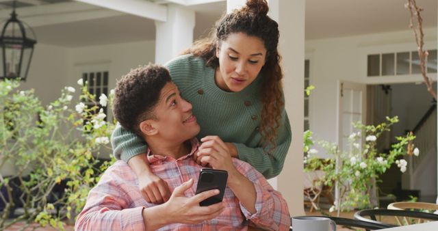 Image of biracial couple using smartphone in the garden. Domestic lifestyle and leisure time at home.