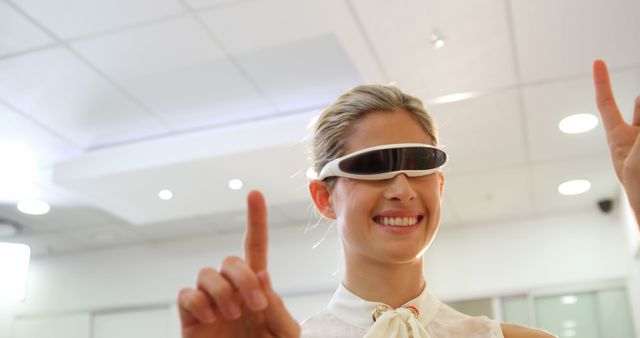 Woman sporting futuristic AR glasses, engaging in a playful yet focused manner. Ideal for technology, innovation, and virtual reality themes. Perfect for corporate brochures, tech articles, and advertisements showcasing cutting-edge office environments.