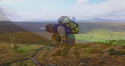 Hiker tying laces on scenic mountain trail overlooking rolling valley