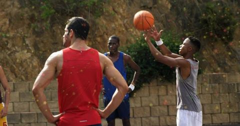 Young Athletes Playing Basketball in Sunlit Outdoor Court