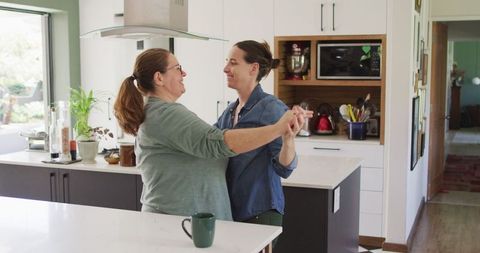 Joyful Lesbian Couple Dancing in Modern Kitchen