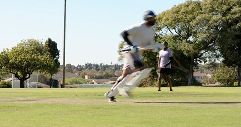 African american cricket batter sprinting into crease swinging bat with motion blur