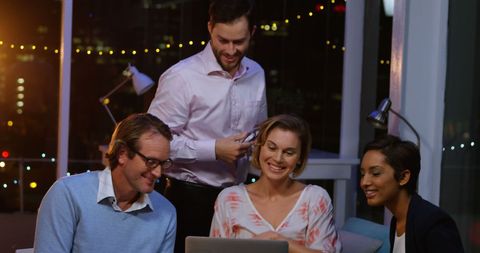 Diverse Business Team Collaborating on Laptop in Office at Night