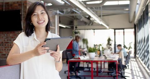 Young professional holding tablet in modern open workspace