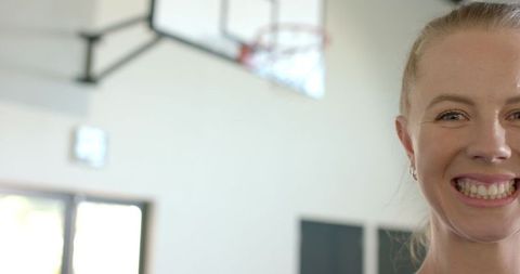 Smiling Woman in Gymnasium near Basketball Hoop