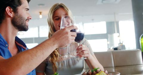 Joyful Couple Toasting Wine at Restaurant Table