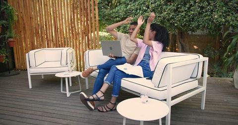 Diverse Couple Using Laptop on Wooden Patio