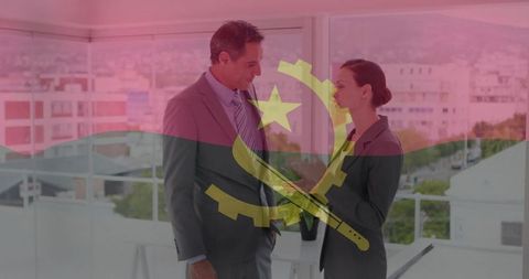 Business colleagues discussing strategy with angola flag overlay in modern glass office