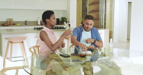 Couple Dining and Assembling Burger at Modern Kitchen Table