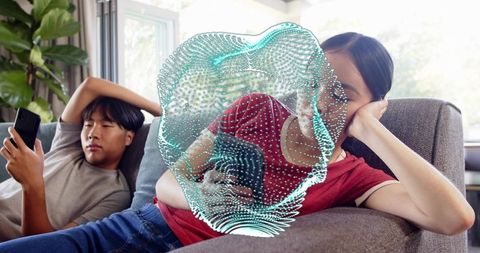 Young couple using smartphones on sofa with turquoise digital overlay representing distraction