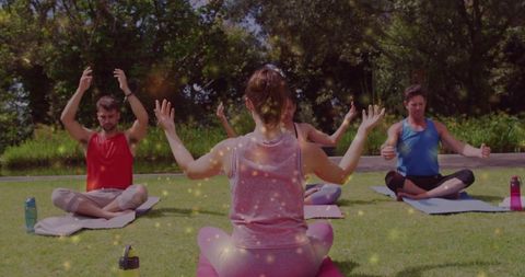 Yoga instructor guiding outdoor group meditation on park lawn, practicing mindful breathing