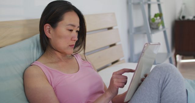 Woman in pink top using digital tablet in bedroom - Download Free Stock Images Pikwizard.com