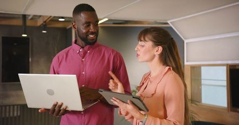 Two Colleagues Collaborating with Laptop and Tablet in Office