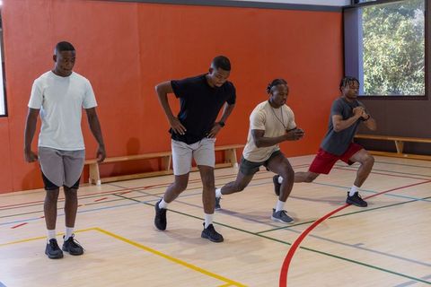 African american men performing lunge drills in indoor gym group fitness training and warmup