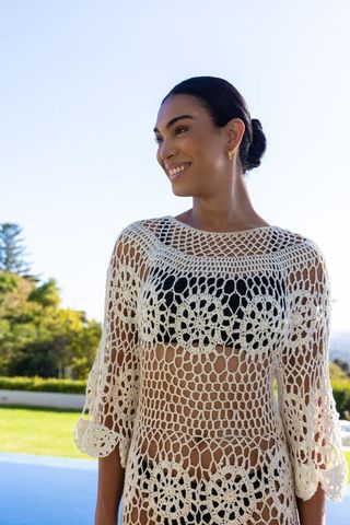 African american woman smiling poolside wearing crochet cover-up over black bikini
