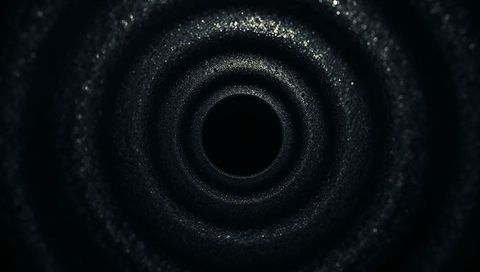 Dark metallic concentric tunnel with sparkling textured rings and central void