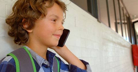 Schoolboy Cheerfully Talking on Mobile Phone in Corridor