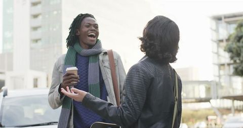 Friends laughing on urban street with coffee and skateboard, youthful street style