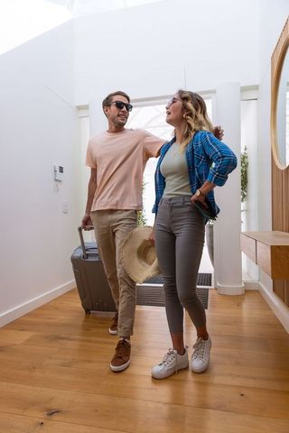 Couple Arriving at Home with Travel Luggage and Fashionable Attire